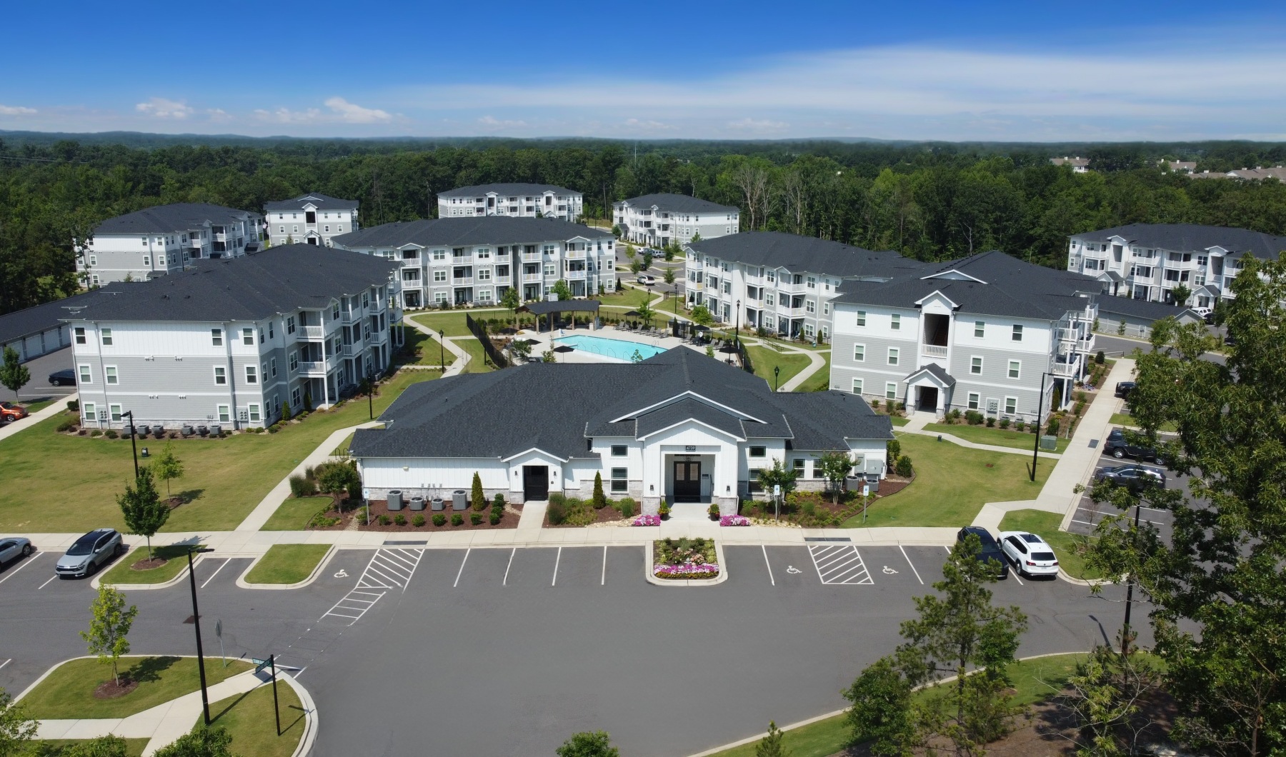 Aerial view of The Caroline Apartments in Indian Land, SC, featuring modern three-story buildings, resort-style pool, and landscaped courtyards.