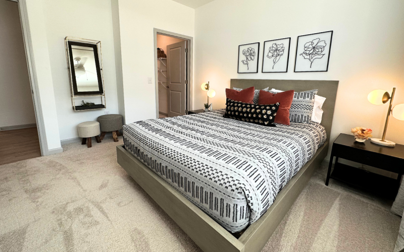 Modern apartment bedroom with large queen bed and walk-in closet