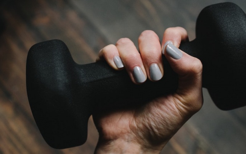 lifestyle image of a hand holding a dumbell